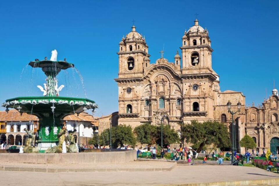 A historic cathedral with twin towers and a fountain in front.