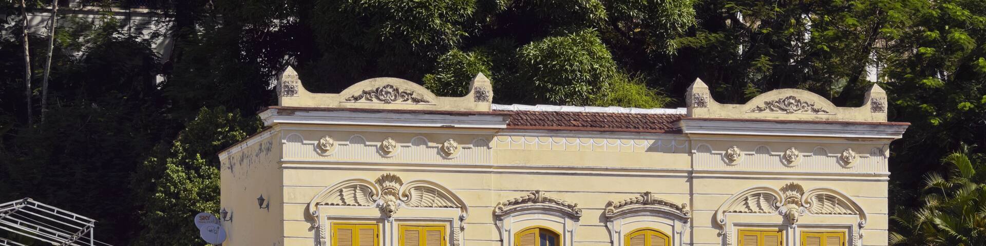 A two-story building with yellow shutters and ornate architectural details.