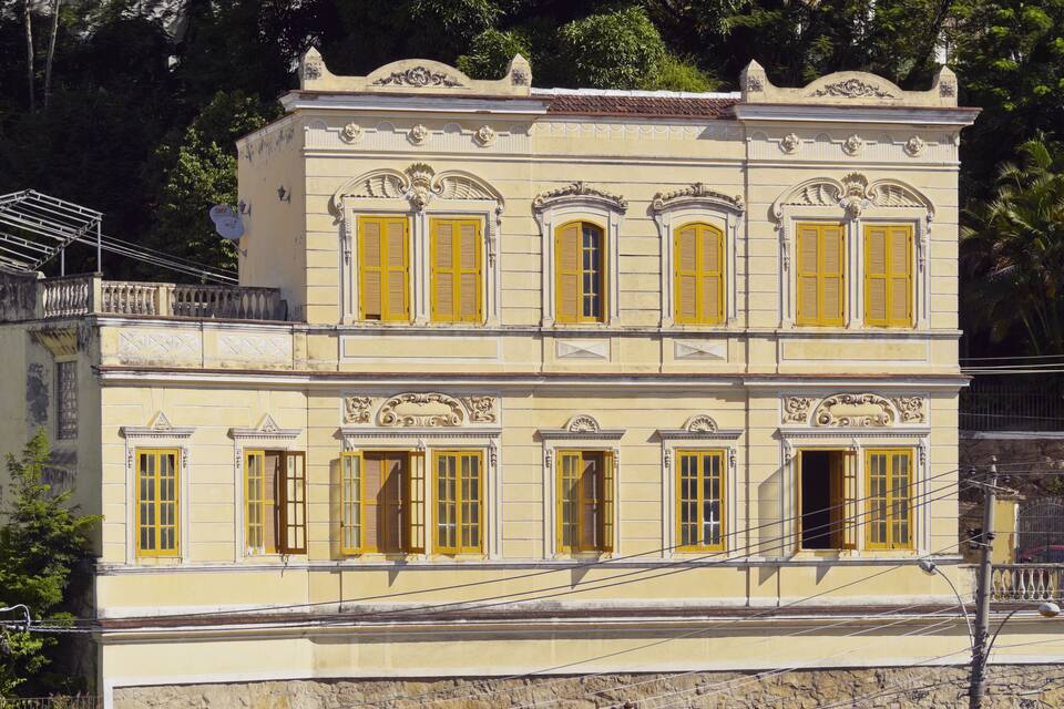 A two-story building with yellow shutters and ornate architectural details.