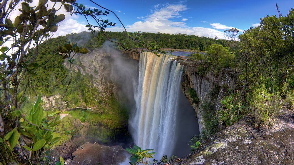 A waterfall cascading down a cliff surrounded by lush greenery.