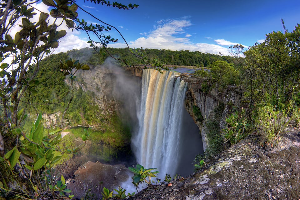 A waterfall cascading down a cliff surrounded by lush greenery.