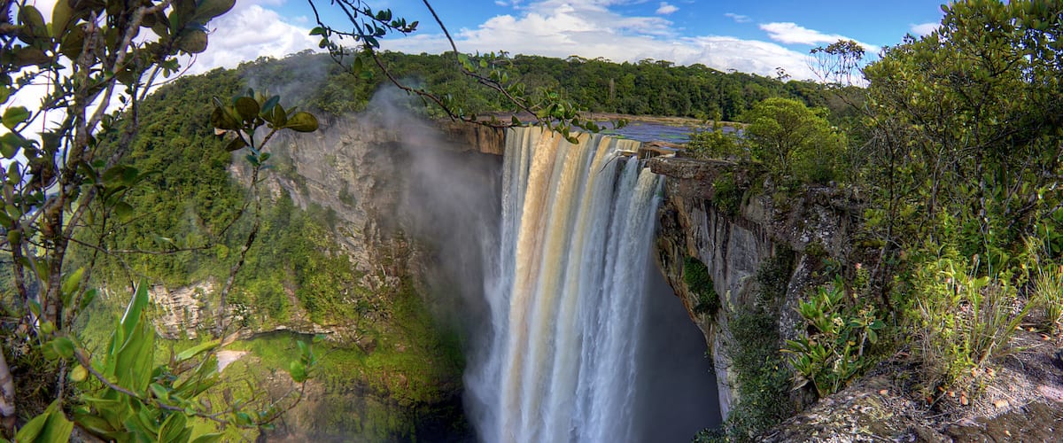 A waterfall cascading down a cliff surrounded by lush greenery.