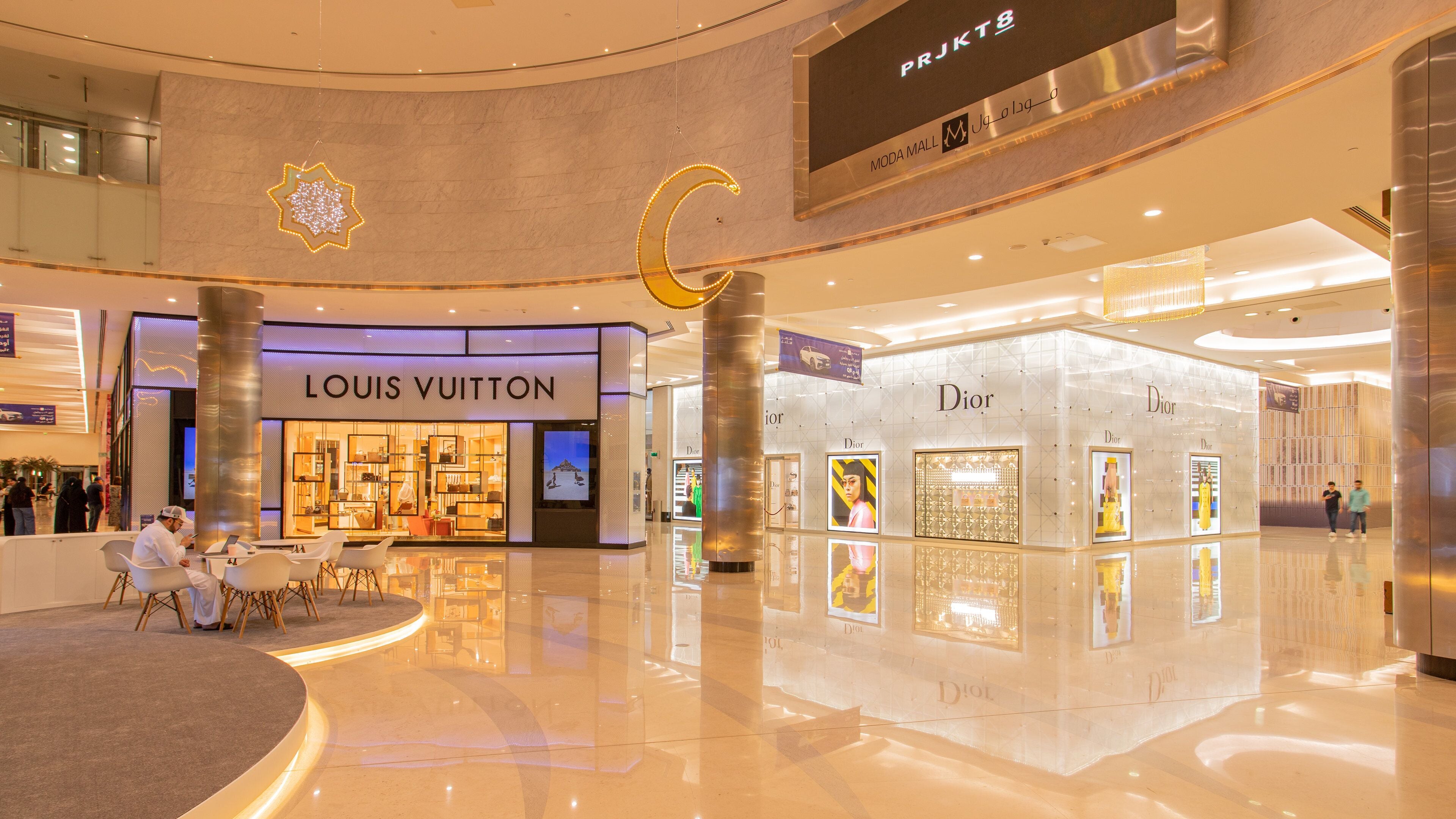 A modern shopping mall interior with Louis Vuitton and Dior stores.