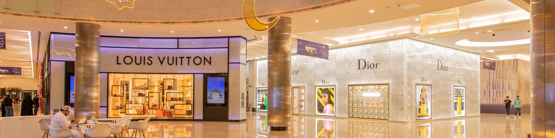 A modern shopping mall interior with Louis Vuitton and Dior stores.
