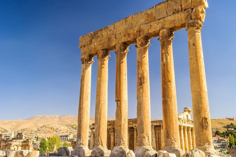 Ancient Greek columns of a historical site with ruins in the background.