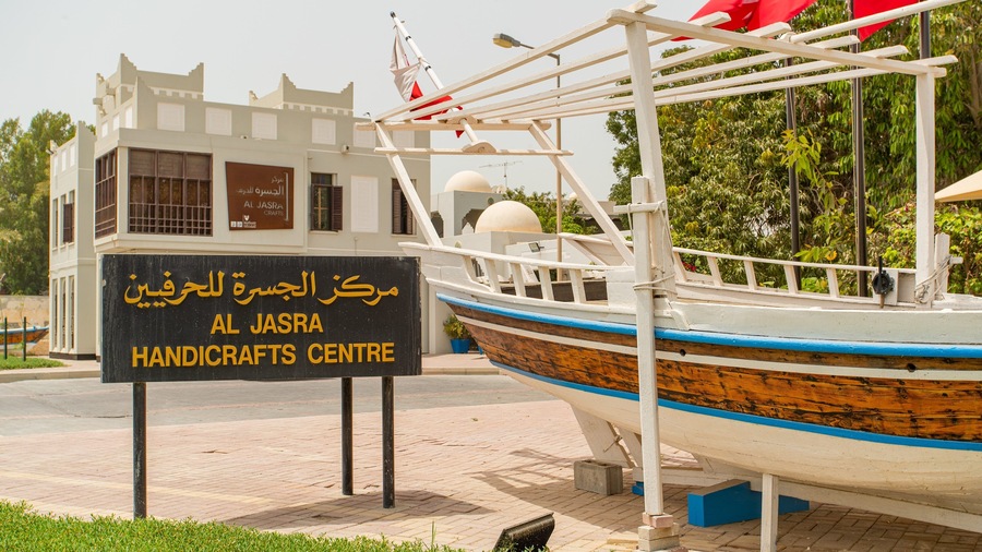 A boat with a sign reading "AL JASRA HANDICRAFTS CENTRE" in Arabic and English.