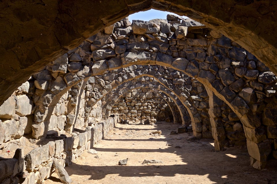 An ancient stone archway with a dirt path leading through it.