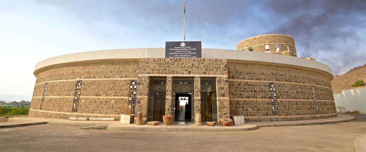 A stone building with a sign reading "Hashemite Kingdom of Jordan Ministry of Tourism & Antiquities Museum at the lowest place on Earth."