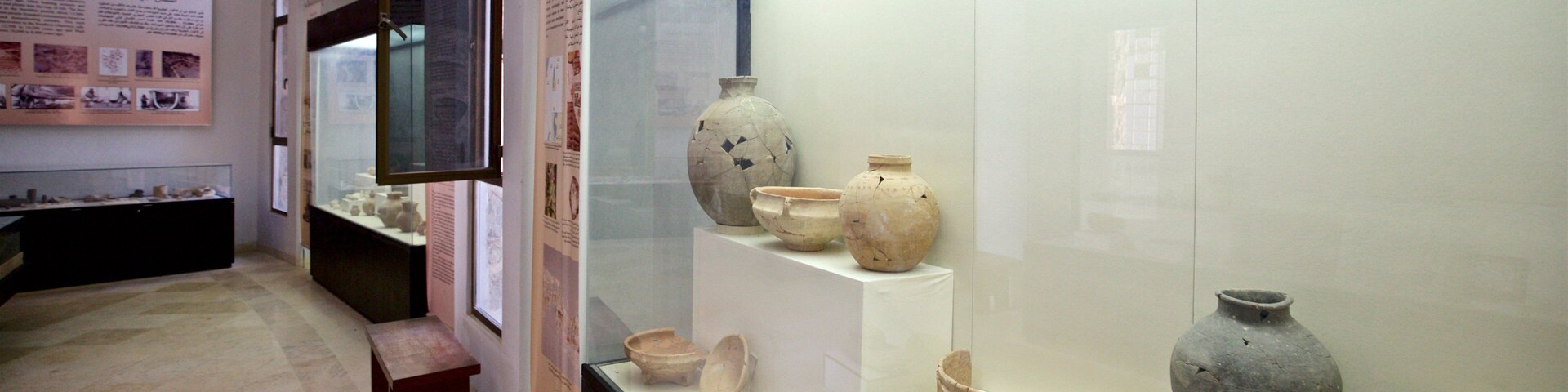 Exposição em museu com cerâmica antiga exposta em prateleiras.
