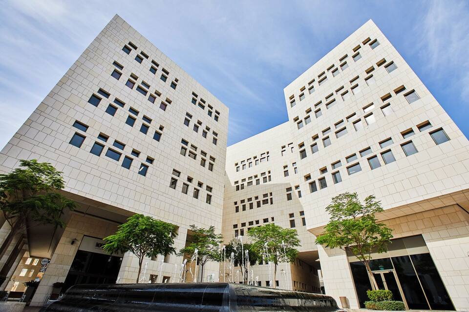 A modern building with a geometric facade and a water feature in front.