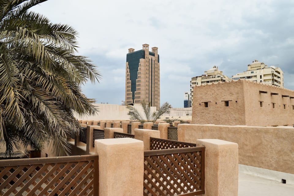 Una palmera, un edificio moderno de gran altura y arquitectura tradicional.