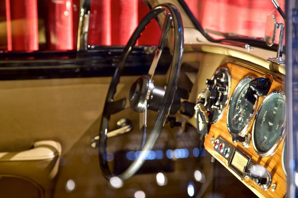 A vintage car dashboard with a steering wheel, speedometer, and other gauges.