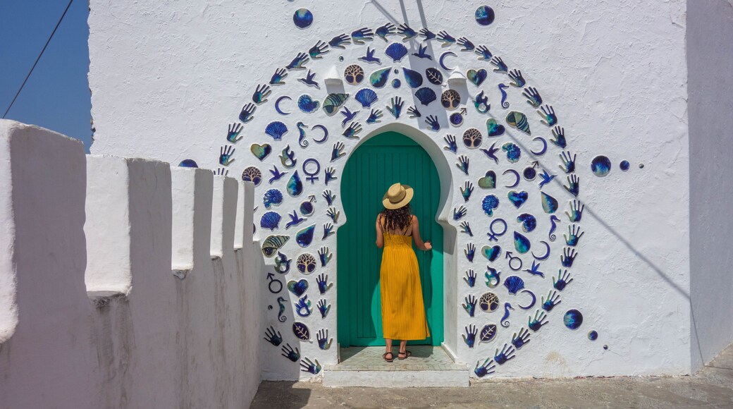 Woman in yellow dress and hat in a nice decorated door of the village of Asilah in Morocco