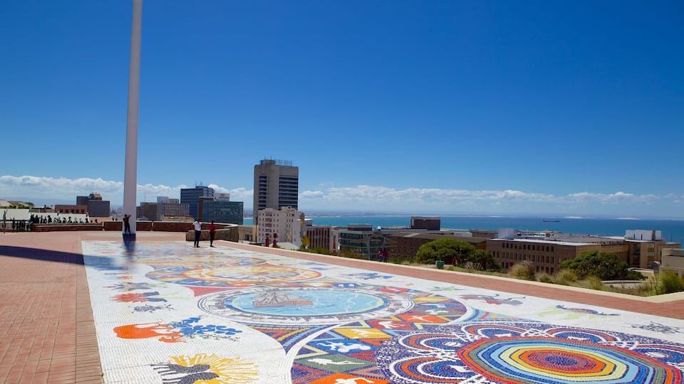 Une mosaïque ornant une place, avec une vue sur la ville et l’océan en arrière-plan.