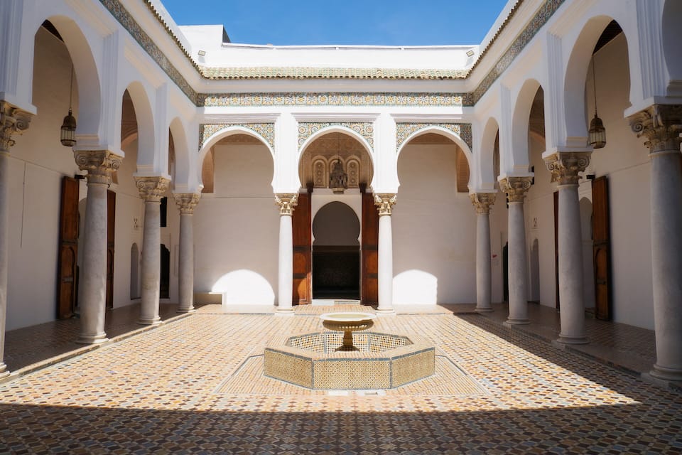 Ein Innenhof mit Bögen, Säulen und einem gemusterten Boden.