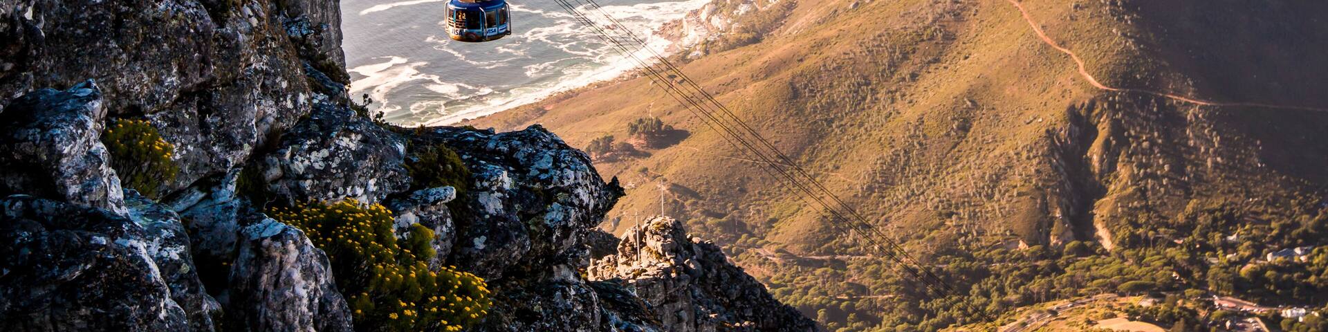Un teleférico sobre un paisaje montañoso con vista al océano.