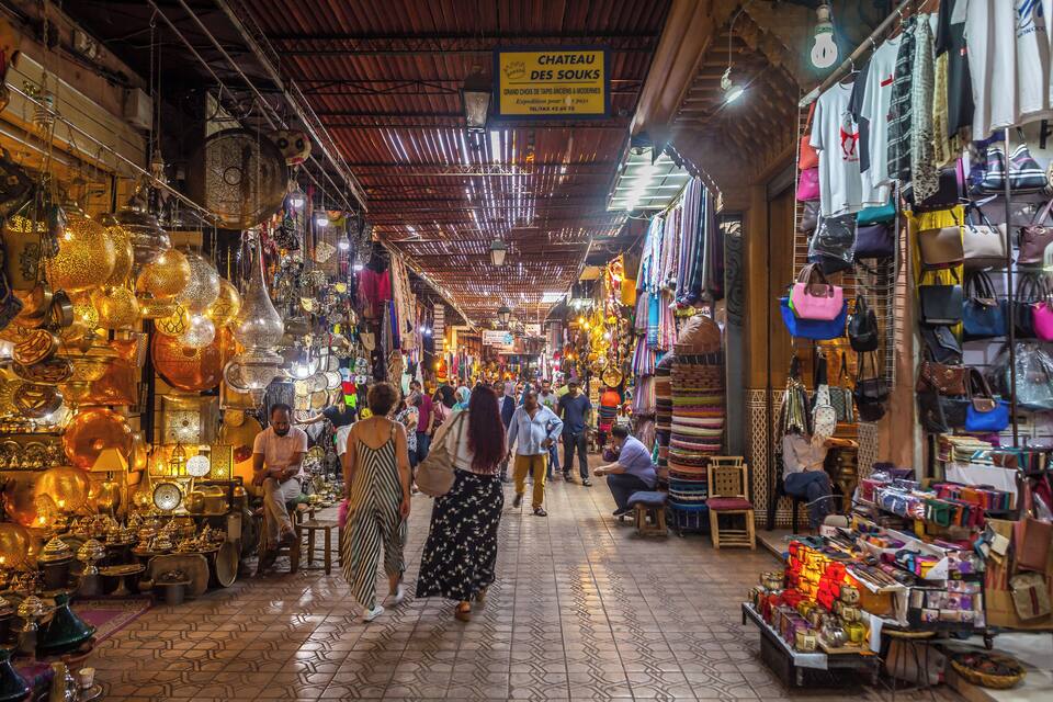 A bustling market with various stalls selling jewelry, bags, and textiles.
