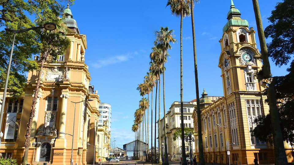Eine Straße gesäumt von Palmen und historischen Gebäuden mit Uhrtürmen.