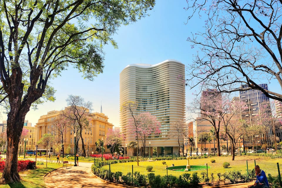 Ein Park mit einem modernen Gebäude, Kirschblüten und einem Brunnen.