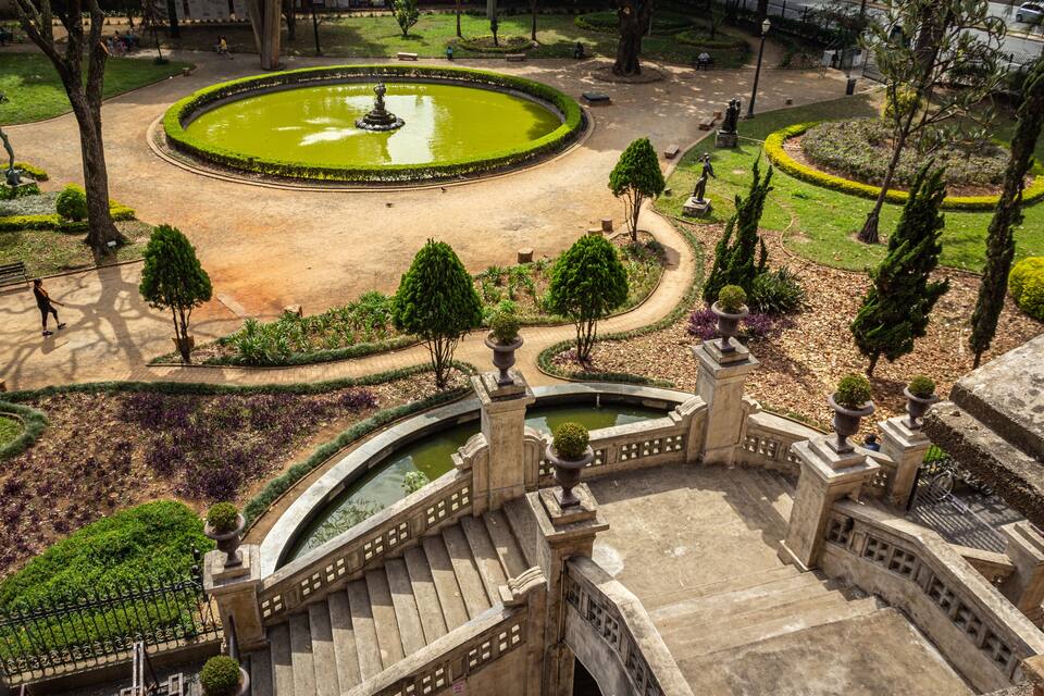 Un parc amb un estany circular, ponts de pedra i jardins ben cuidats.