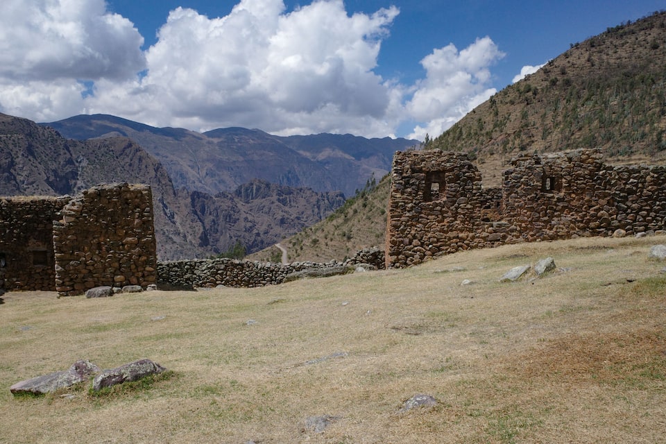 Antiguas ruinas de piedra en un paisaje montañoso bajo un cielo despejado.