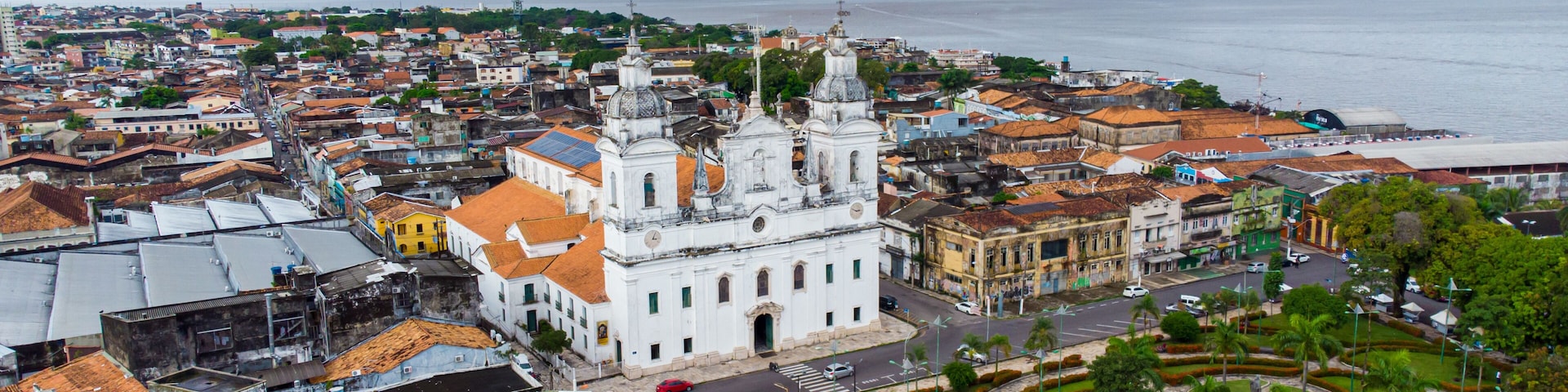 A coastal cityscape with a prominent white church, a circular garden, and a view of the sea.