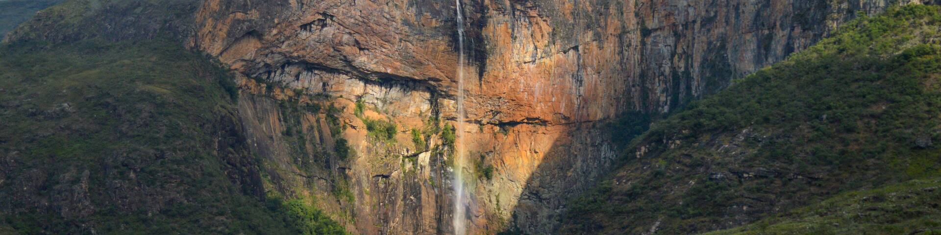 A waterfall cascading down a steep cliff surrounded by lush greenery.