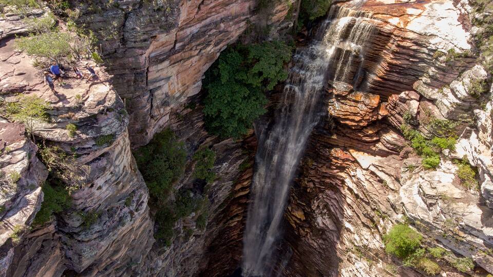 A waterfall cascading down a rocky cliff with a narrow opening at the base.