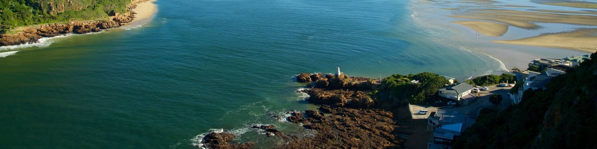Un paysage côtier avec une rivière, une côte rocheuse et un phare.