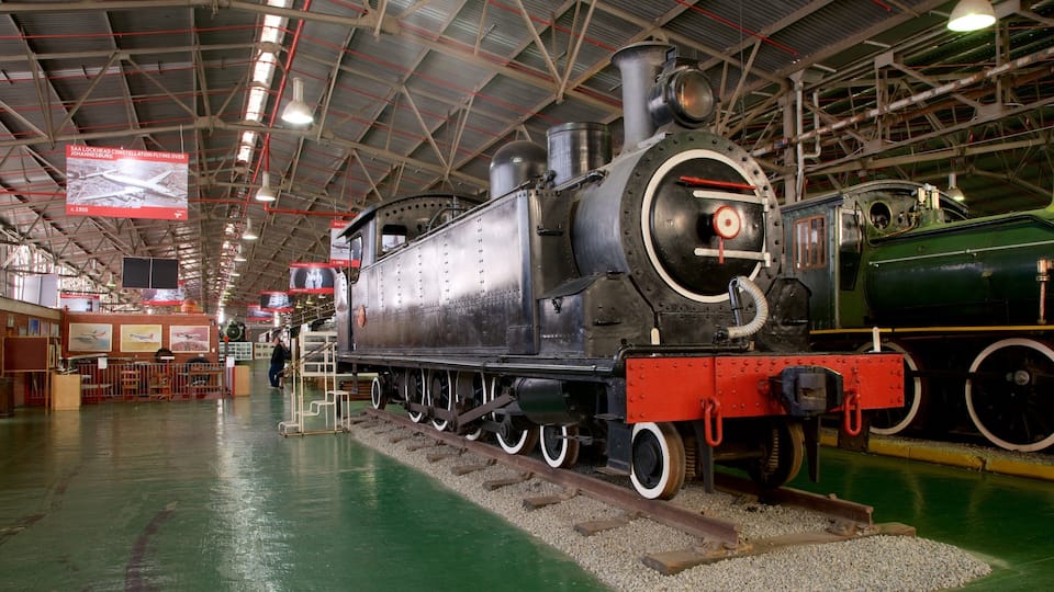 A large steam locomotive in a museum with a green floor and red tracks.