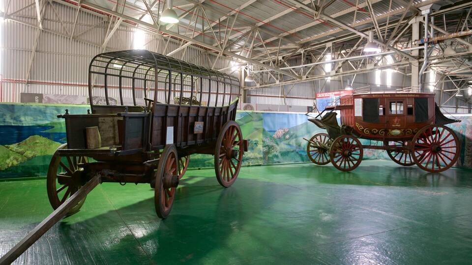 Two vintage carriages in a museum with a green floor and a mural in the background.
