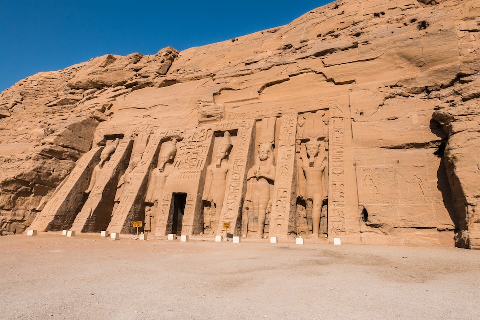 Un vaste temple en grès, orné de hiéroglyphes et flanqué d’une série de colonnes hautes et étroites.