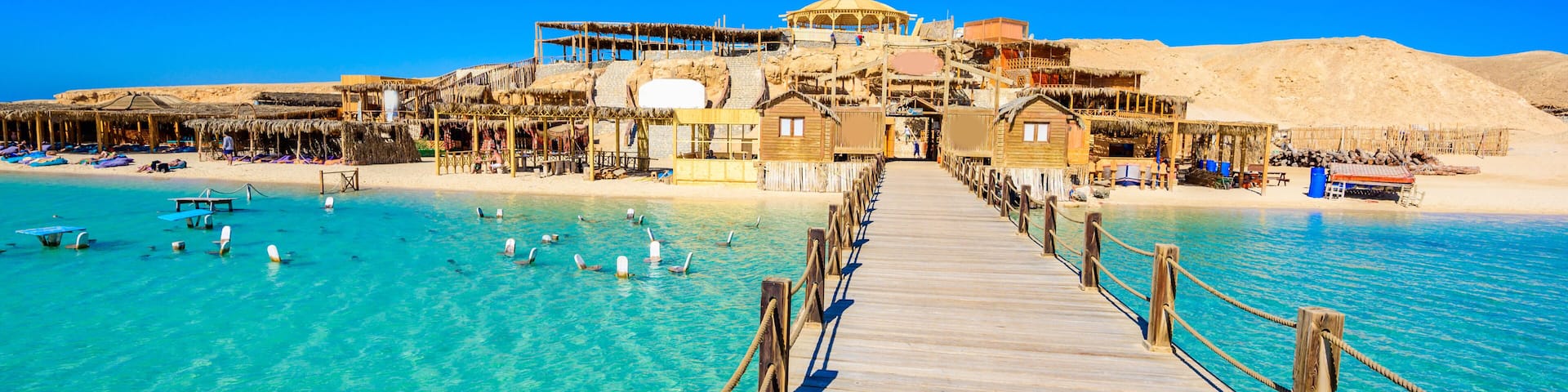 Wooden Pier at Orange Bay Beach with crystal clear azure water and white beach - paradise coastline of Giftun island, Mahmya, Hurghada, Red Sea, Egypt.
