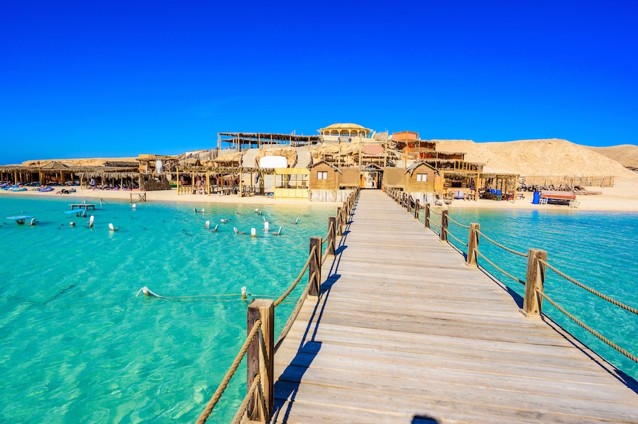 Wooden Pier at Orange Bay Beach with crystal clear azure water and white beach - paradise coastline of Giftun island, Mahmya, Hurghada, Red Sea, Egypt.