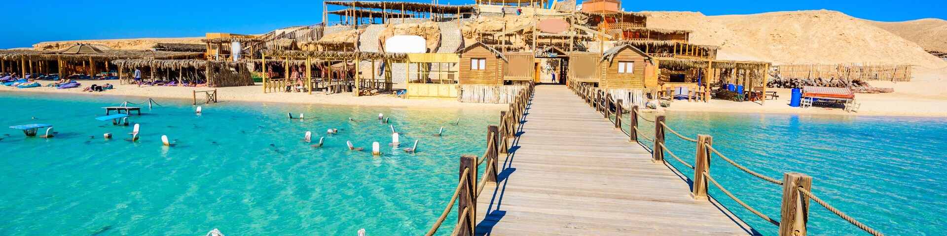 Wooden Pier at Orange Bay Beach with crystal clear azure water and white beach - paradise coastline of Giftun island, Mahmya, Hurghada, Red Sea, Egypt.