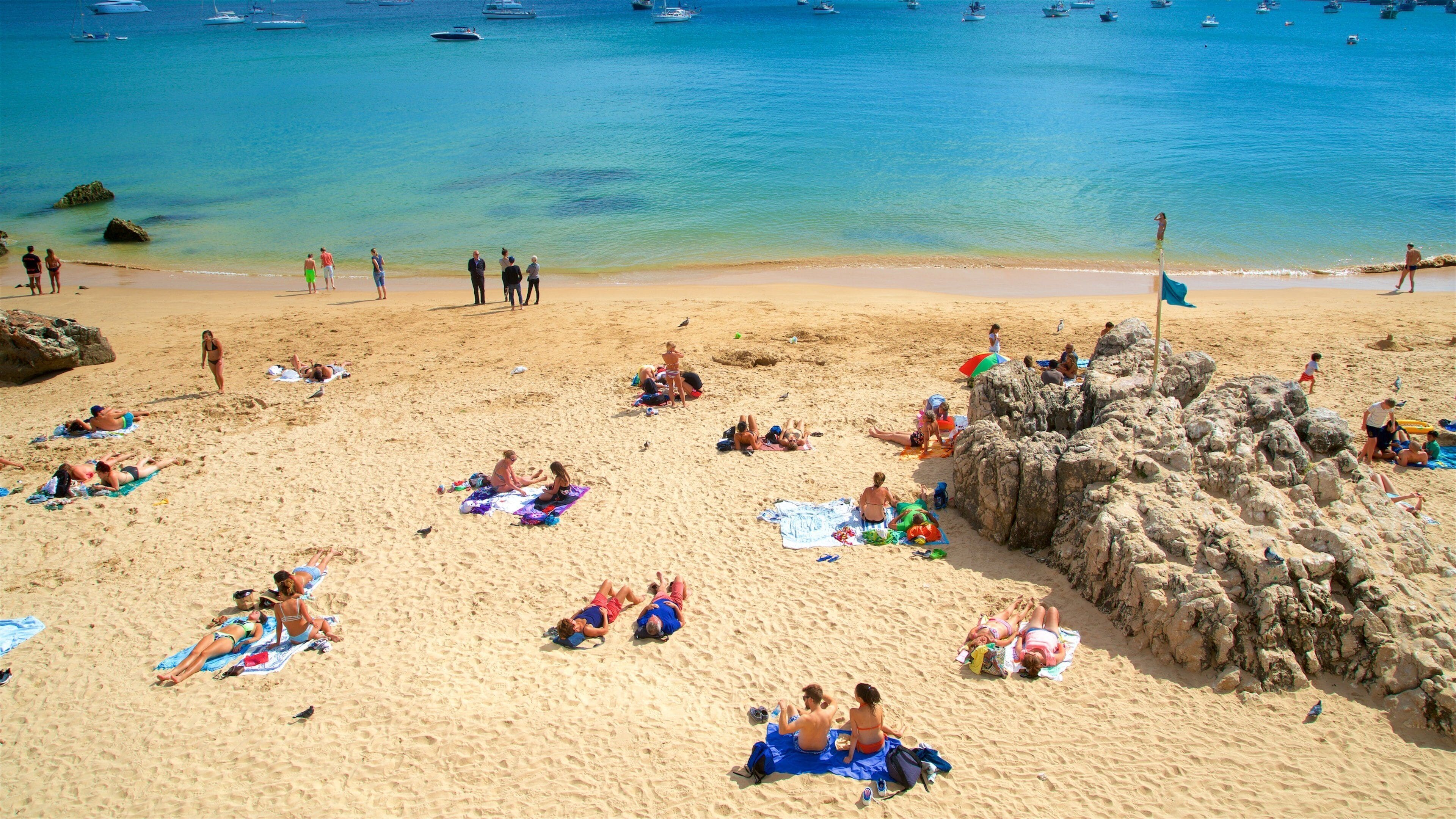 Rainha Beach which includes general coastal views and a sandy beach as well as a small group of people