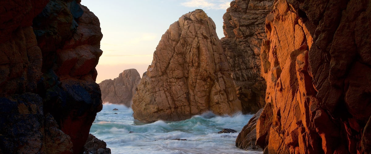 A coastal rock formation with waves crashing against it.