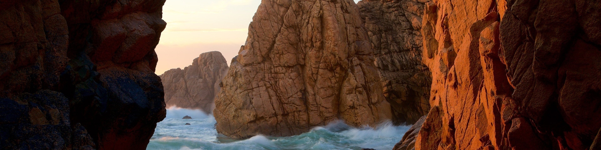 A coastal rock formation with waves crashing against it.