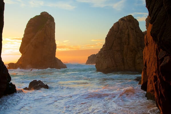 Ursa Beach featuring surf, a sunset and rugged coastline