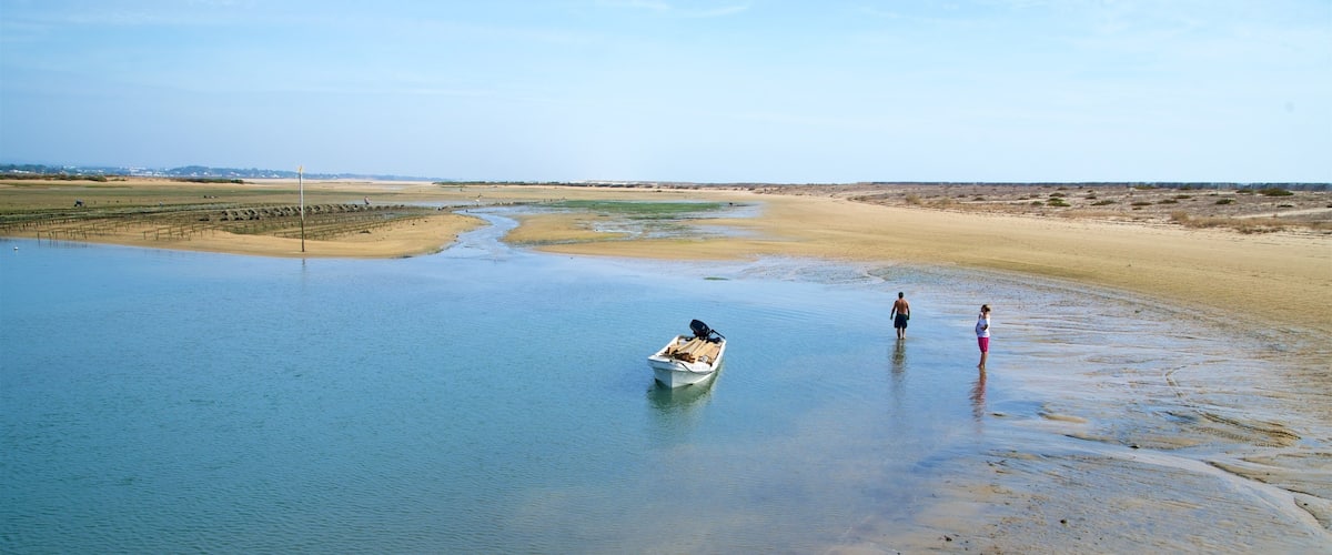 Fuzeta Beach montrant scÚnes tranquilles et lac ou étang aussi bien que couple