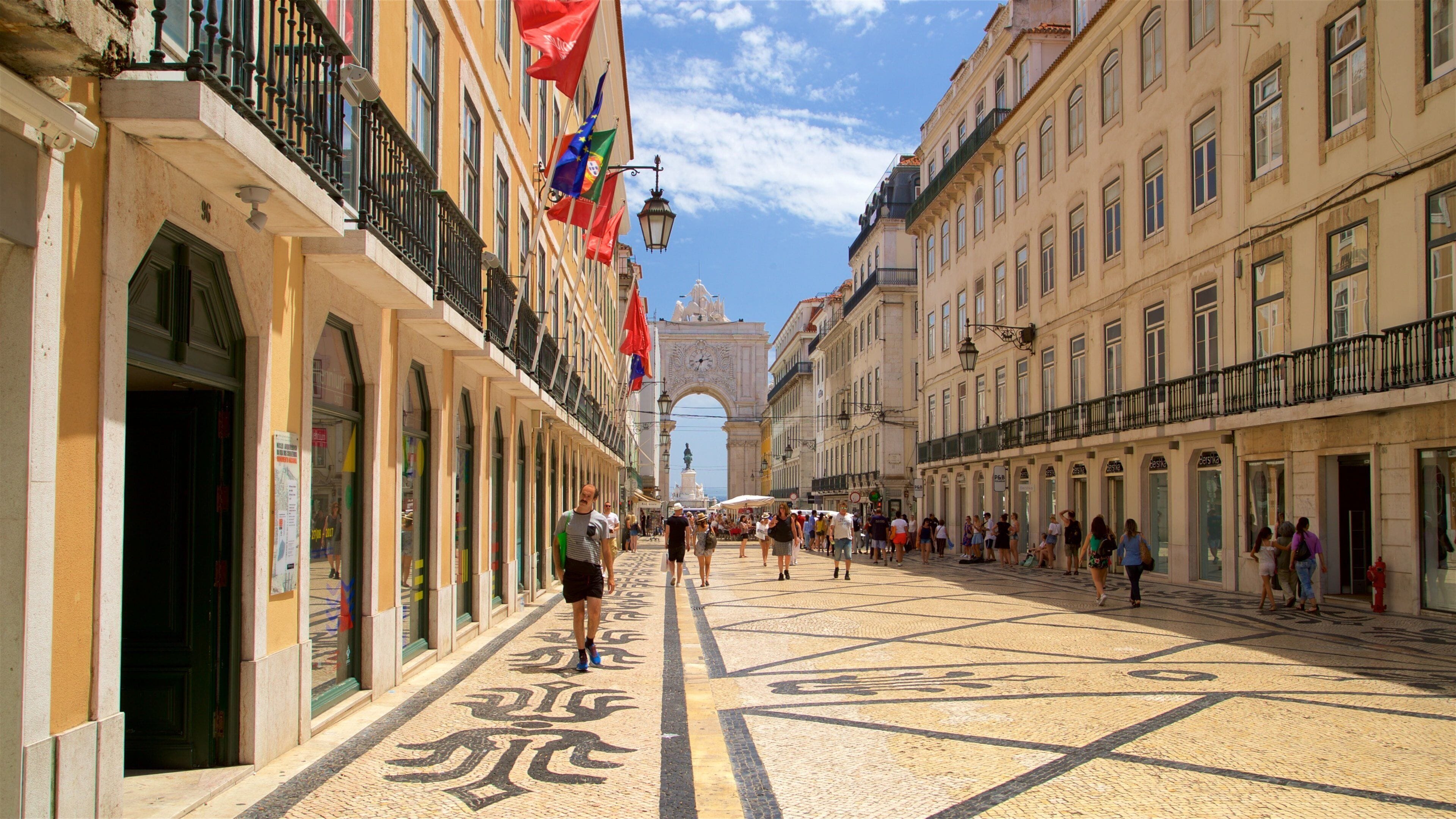 A bustling street with historic buildings, a prominent archway, and a tiled pavement.