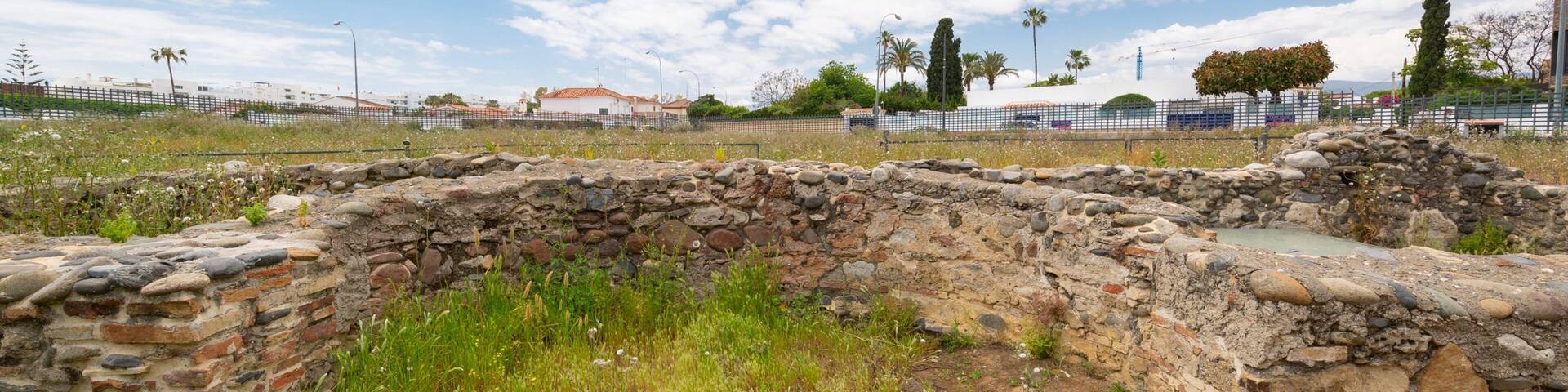 Ancient stone ruins with a stone wall and a grassy field.