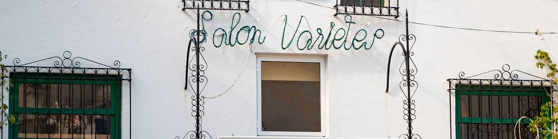 A white building with green shutters and a sign that reads "Salon Varlet."