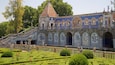 Ein historisches Gebäude mit aufwendigen blauen und weißen Fliesen, einem markanten Turm und einem gepflegten Garten mit Hecken und Blumen.