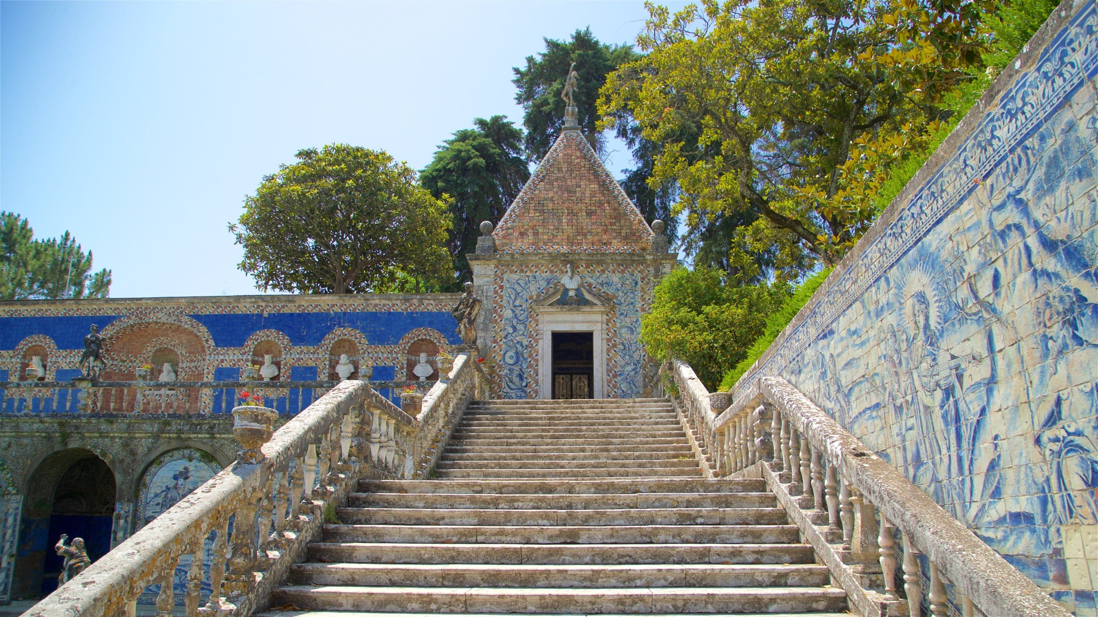 A staircase leading to a tiled building with a statue on top.