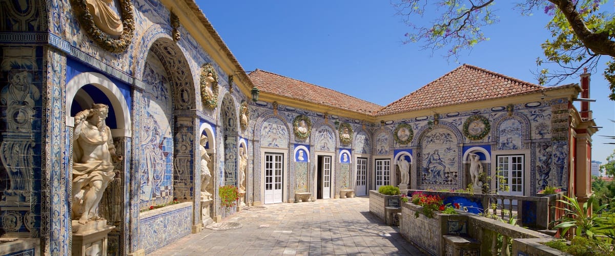 A courtyard with blue and white tiled walls, statues, and a tiled roof.