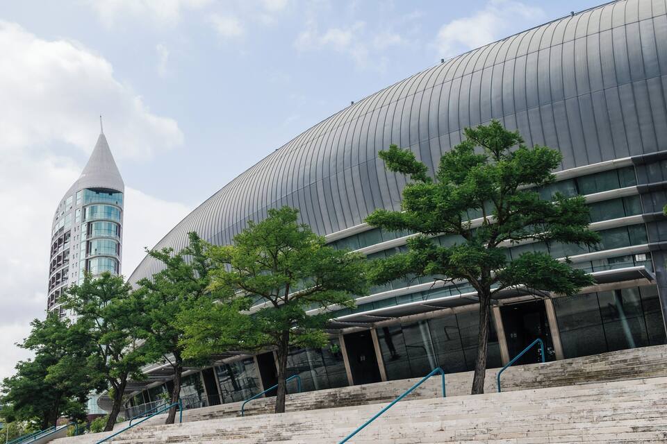 A modern building with a curved facade and a tower with a pointed top.