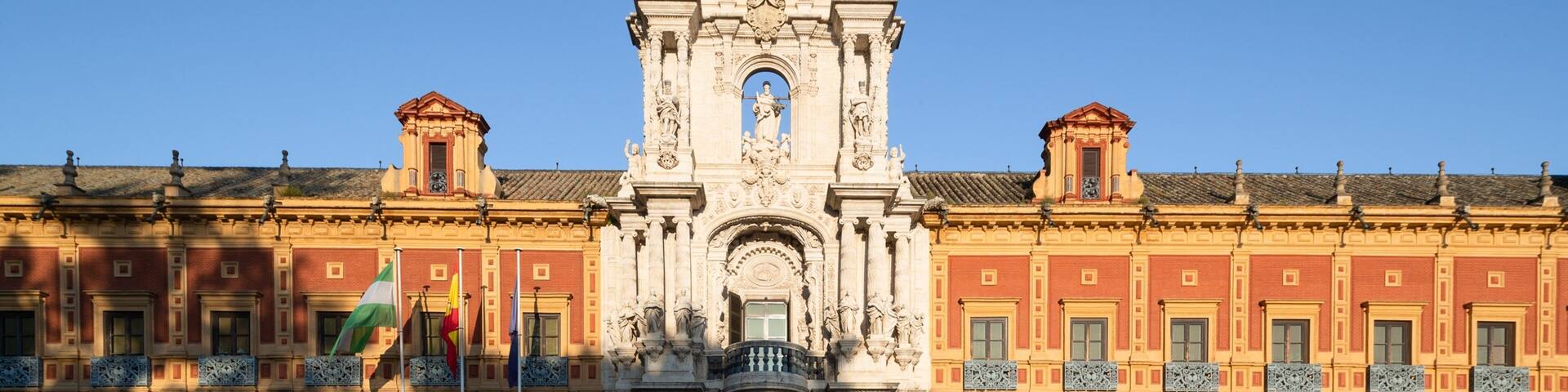 A grand building with a central entrance, ornate columns, and a clock tower.