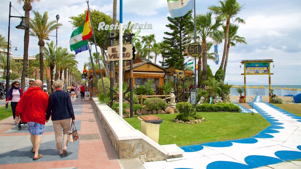 A coastal promenade with palm trees, a restaurant named 'El Vero', and a beach in the background.