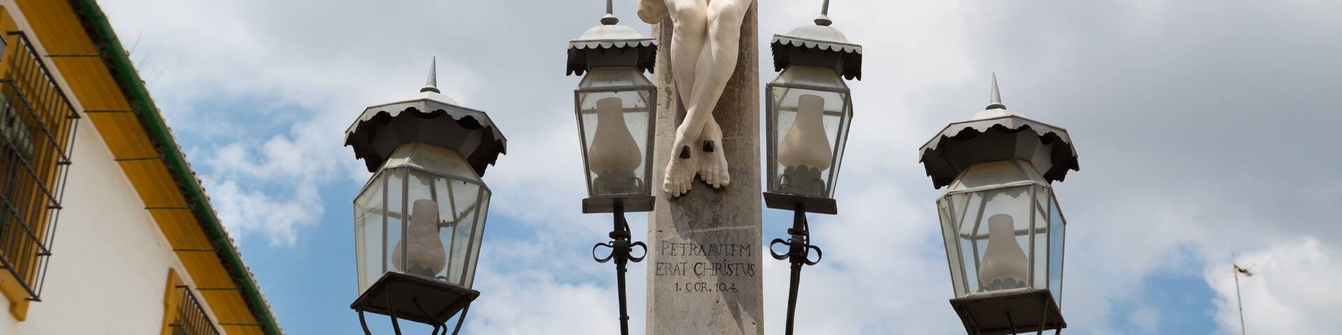 A crucifixion statue with three lanterns on either side.